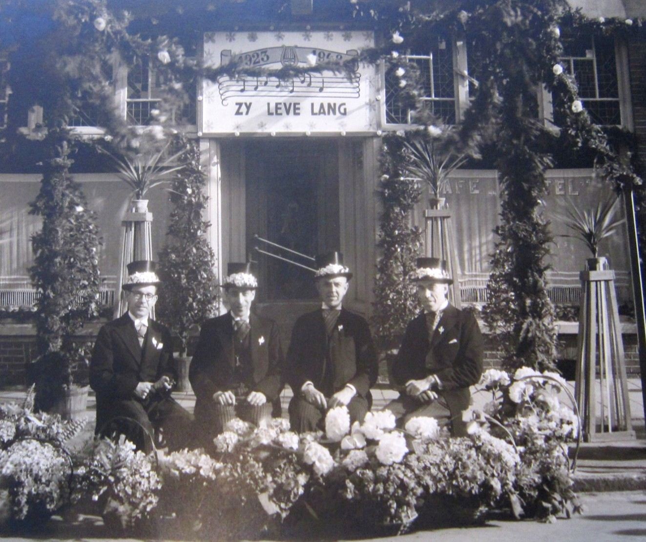 De eerste jubilarissen onder een erepoort met „Zij leven lang”, 1936