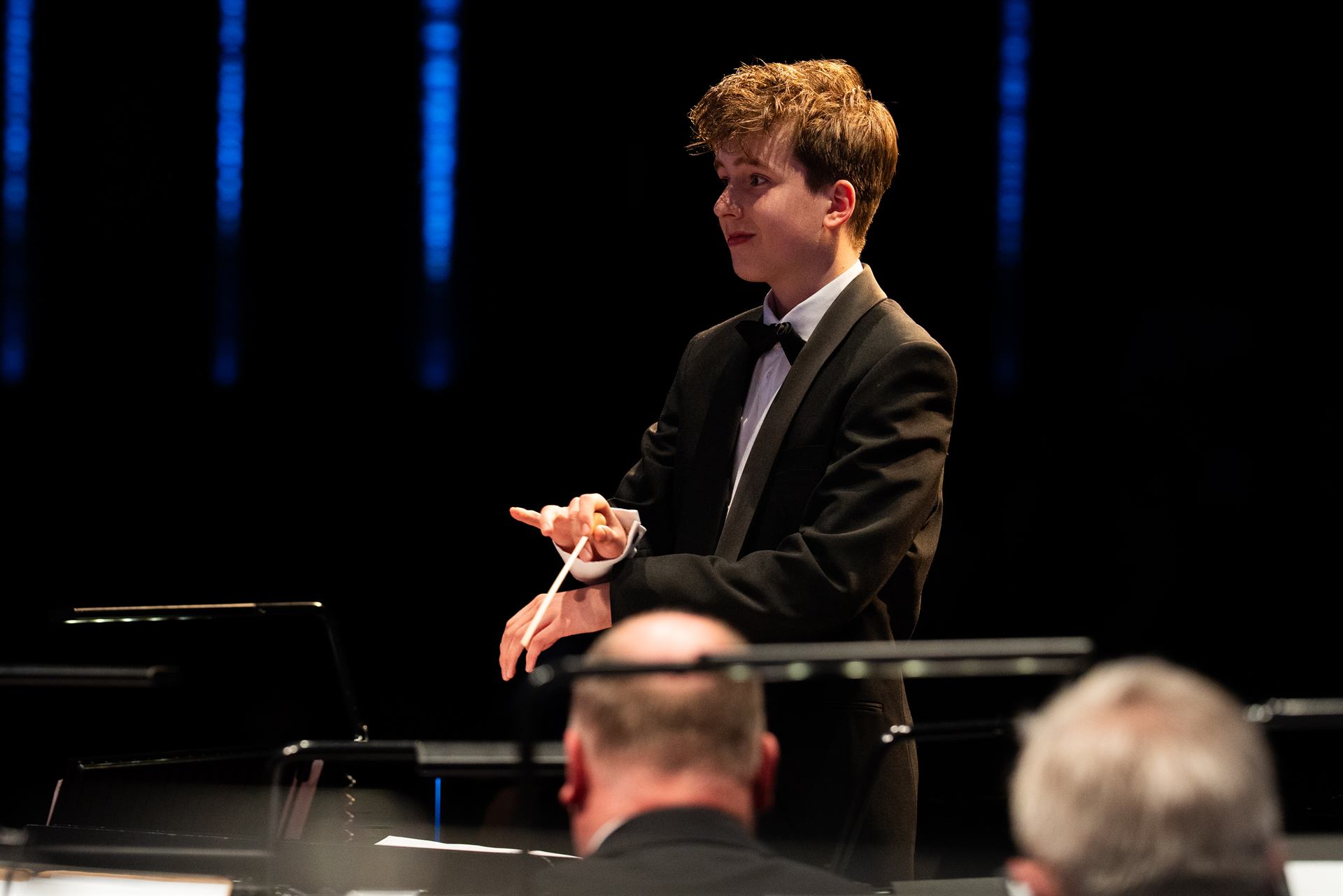 Een jonge gastdirigent in smoking voor het orkest